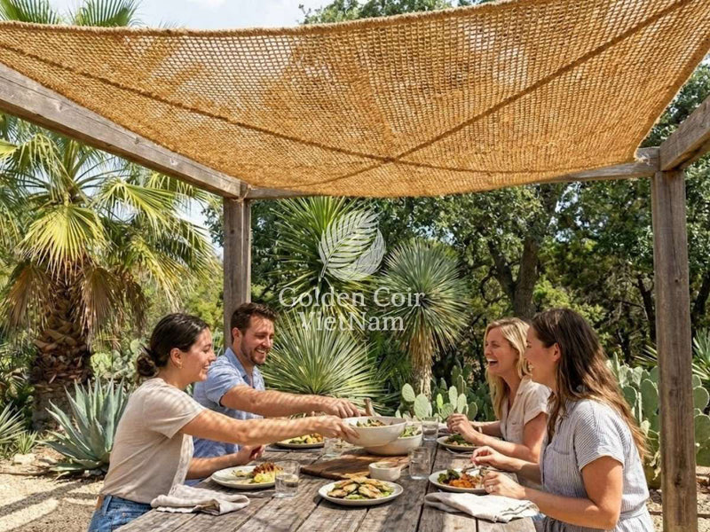 Friends dining under a natural fiber shade sail on a wooden pergola, creating breathable, eco-friendly patio shade for outdoor living.