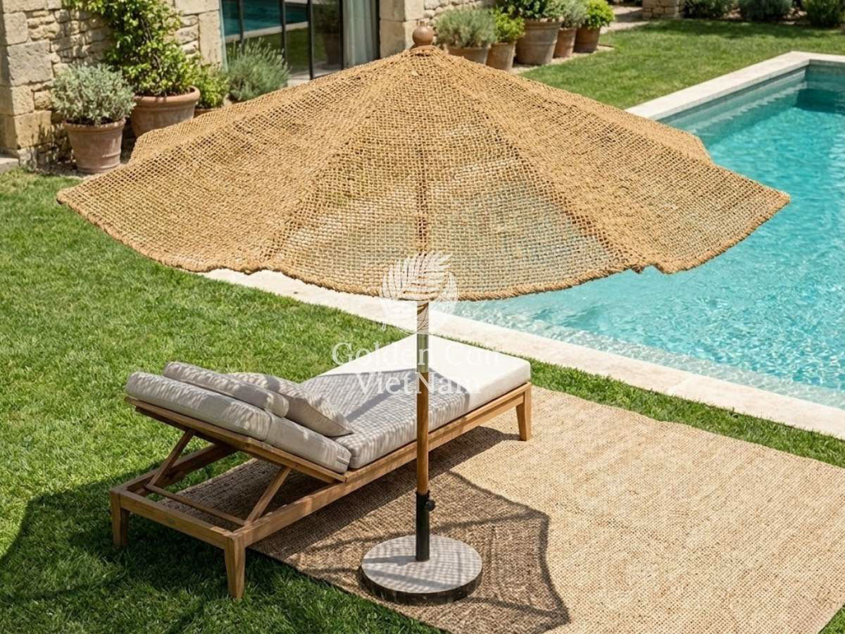 Coco umbrella woven natural-fiber patio umbrella shading a poolside lounge chair in a backyard garden
