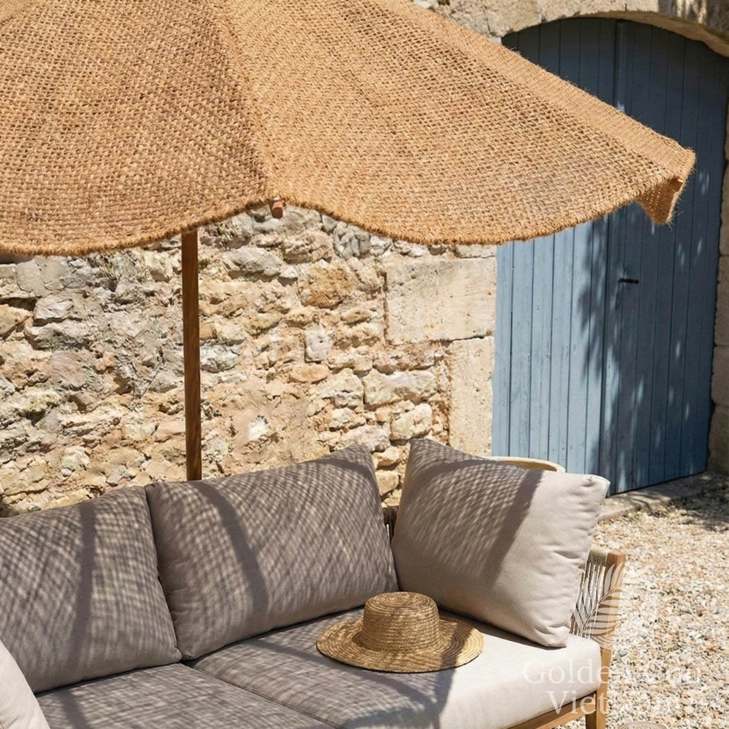 Outdoor seating area with a thatched umbrella, stone wall, and blue door.